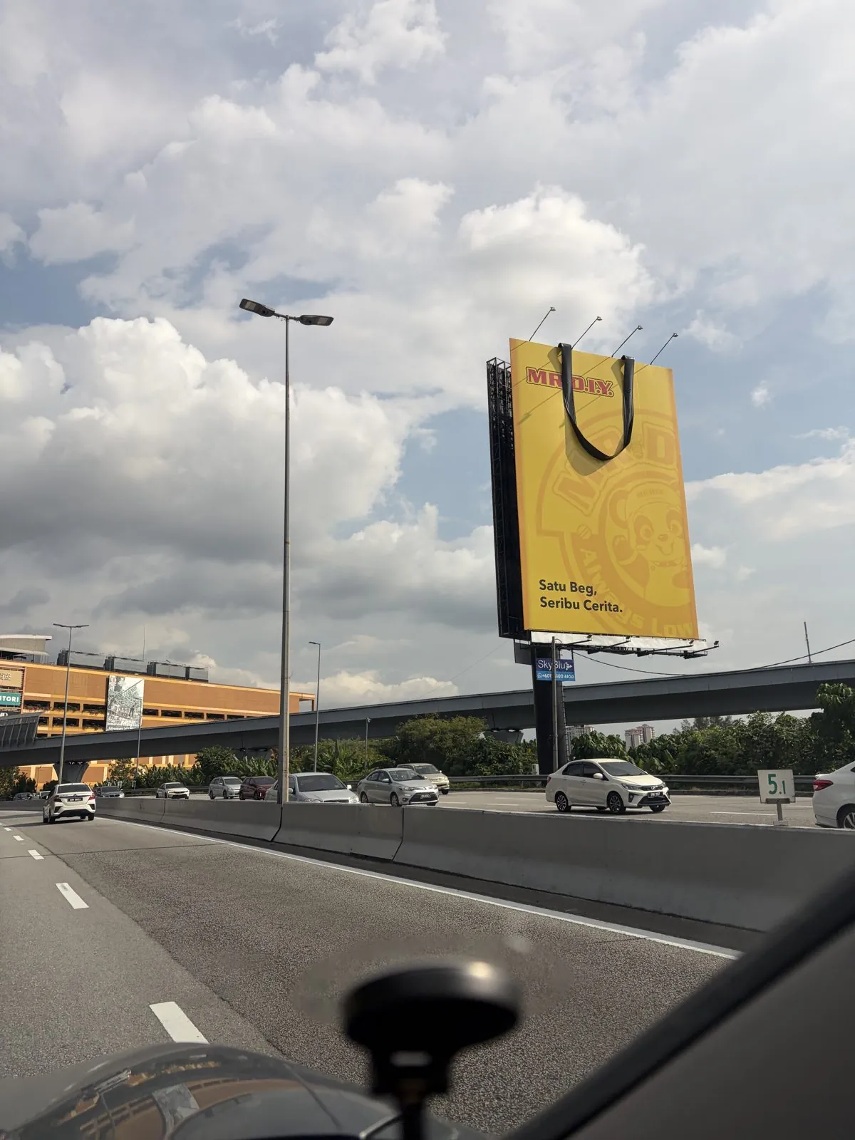 MR D.I.Y. yellow bag billboard with a protruding 3D black handle above a Klang Valley highway, Satu Beg Seribu Cerita campaign